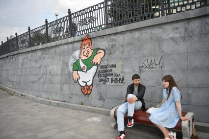 Екатеринбург. Влюбленные сидят на набережной реки Исеть, у граффити Карлсона