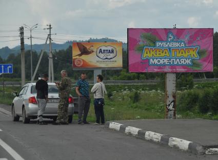 Республика Алтай. Водители стоят у рекламных щитов на федеральной трассе   `Чуйский тракт`.