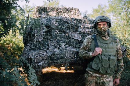 Запорожская область. Боец с позывным `Крокодил` рядом с замаскированным броневиком 3-СТС `Ахмат`.