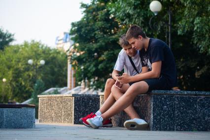 Ростов на Дону. Подростки с мобильным телефоном сидят на улице.