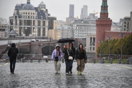 Москва. Девушки гуляют под зонтом  на Красной площади во время дождя.