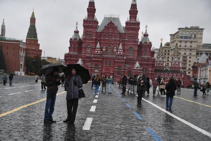 Москва.  Прохожие  на Красной площади во время дождя.