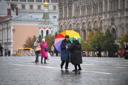 Москва.  Женщины  под зонтом на Красной площади во время дождя.