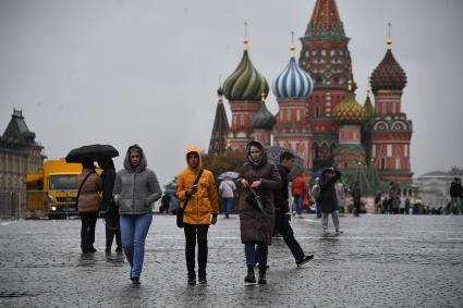 Москва.  Прохожие  на Красной площади во время дождя.