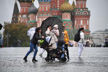 Москва.  Женщина с детьми на Красной площади во время дождя.