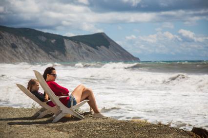 Анапа. Женщина с девочкой сидят на шезлонгах на берегу Черного моря в районе Высокого берега.
