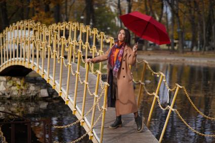 Самара. Девушка стоит на мосту под зонтом красного цветы.