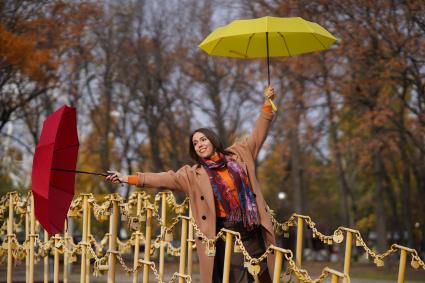 Самара. Девушка на мосту держит в руках красный и желтый зонтики.