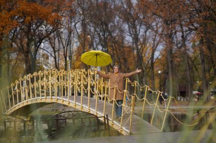 Самара. Женщина стоит на мосту с зонтом желтого цвета.