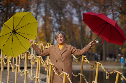 Самара. Женщина на мосту держит в руках красный и желтый зонтики.