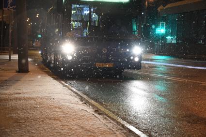 Москва. Автобус движется по вечерней улице во время снегопада.