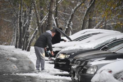 Москва. Мужчина очищает  машину от снега.