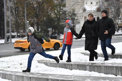 Москва. Мальчик перепрыгивает черех  лужу.