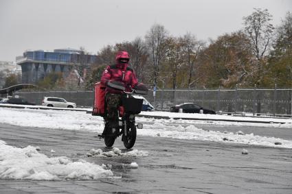 Москва. Сотрудник службы доставки на улице города во время снегопада.