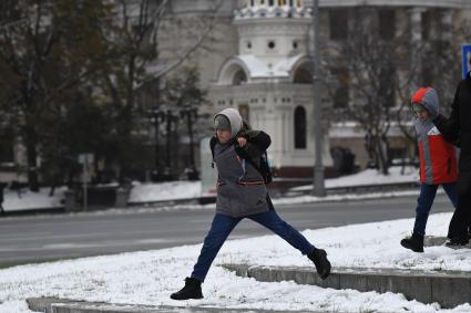 Москва. Мальчик перепрыгивает черех  лужу.