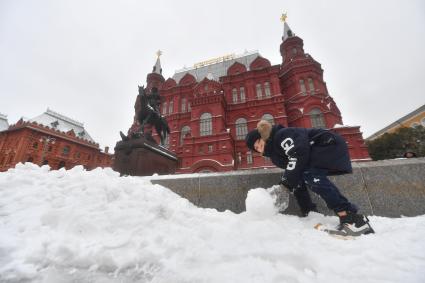 Москва. Мальчик лепит снеговика на Манежной площади у Исторического музея.