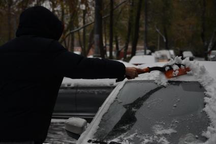 Москва. Автовладелец счищает снег с машины.