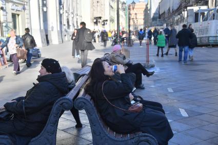 Москва. Женщина сидит на скамейке на Никольской улице.