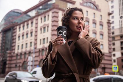 Москва.  Девушка пьет кофе на улице.