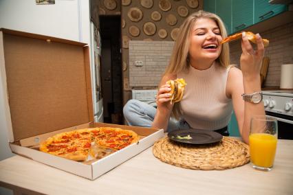Москва.  Девушка ест пиццу дома.