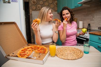 Москва.  Девушки дома едят пиццу и свежие овощи.