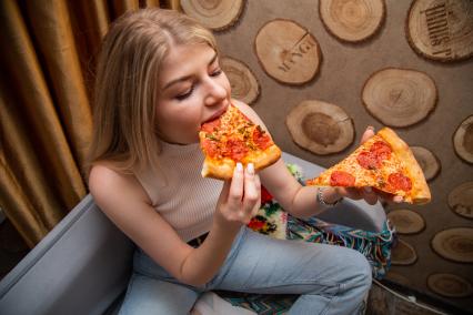 Москва. Девушка дома ест пиццу.