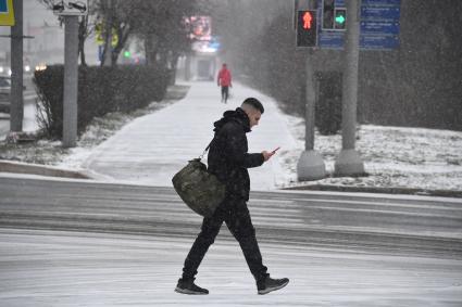 Мужчина с мобильным телефоном идет по улице.