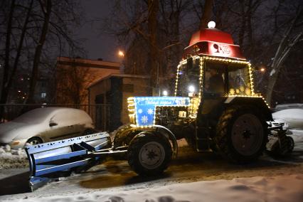 Трактор с новогодним дзайном убирает снег