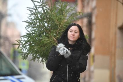 Девушка выбрасывает живую новогоднюю елку