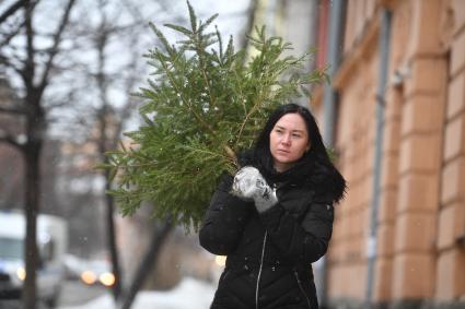 Девушка выбрасывает живую новогоднюю елку