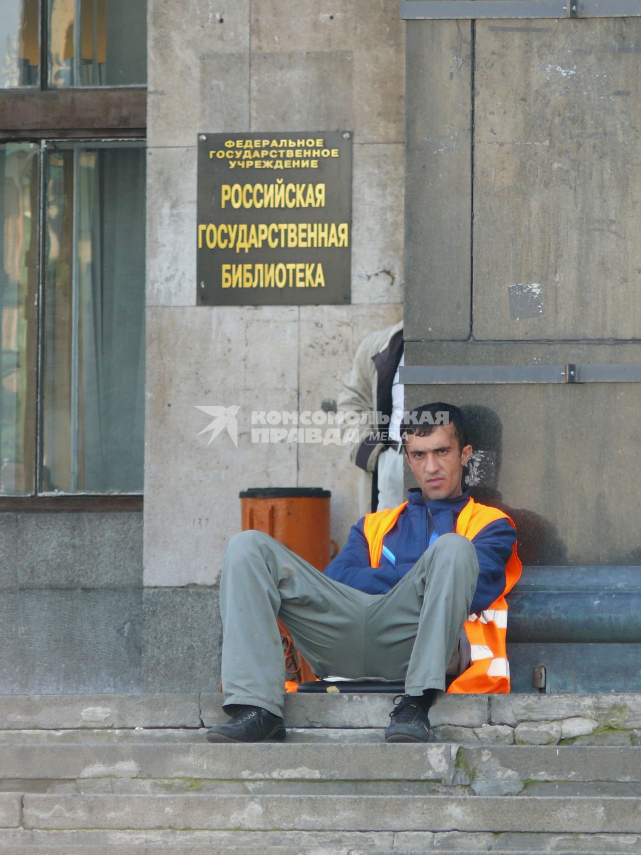 Гастарбайтер сидит на ступеньках у входа в Российскую государственную Библиотеку