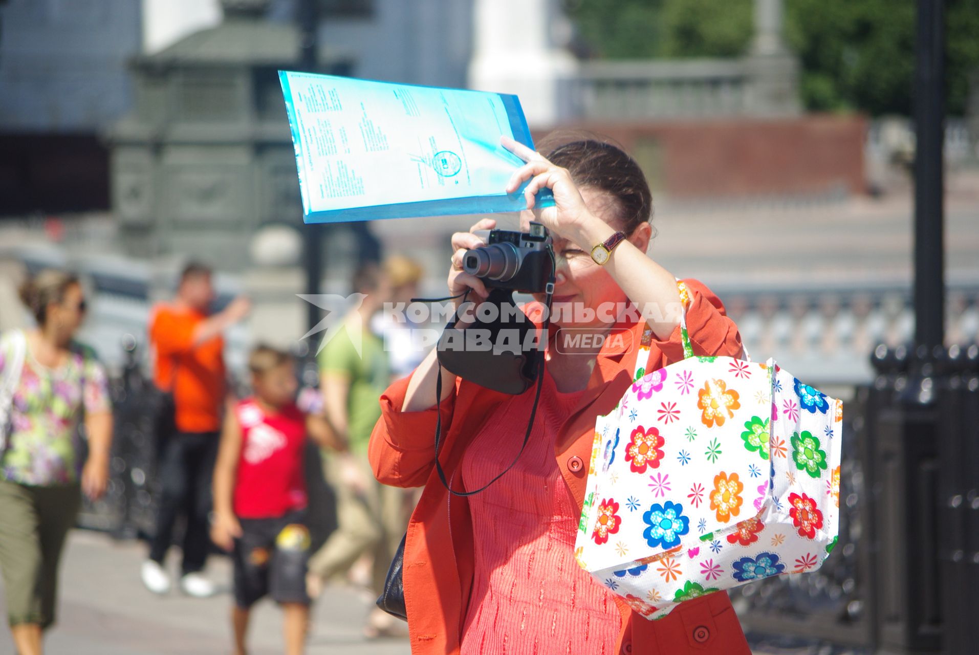 Туристка фотографирует достопримечательности города, документами прикрывая лицо от солнца, 30 июня 2010 года. Жара. Лето. Женщина. Туристка. Фотоаппарат. Солнце. Зной. Достопримечательности. Туризм. Отдых. Папарацци. Документы.