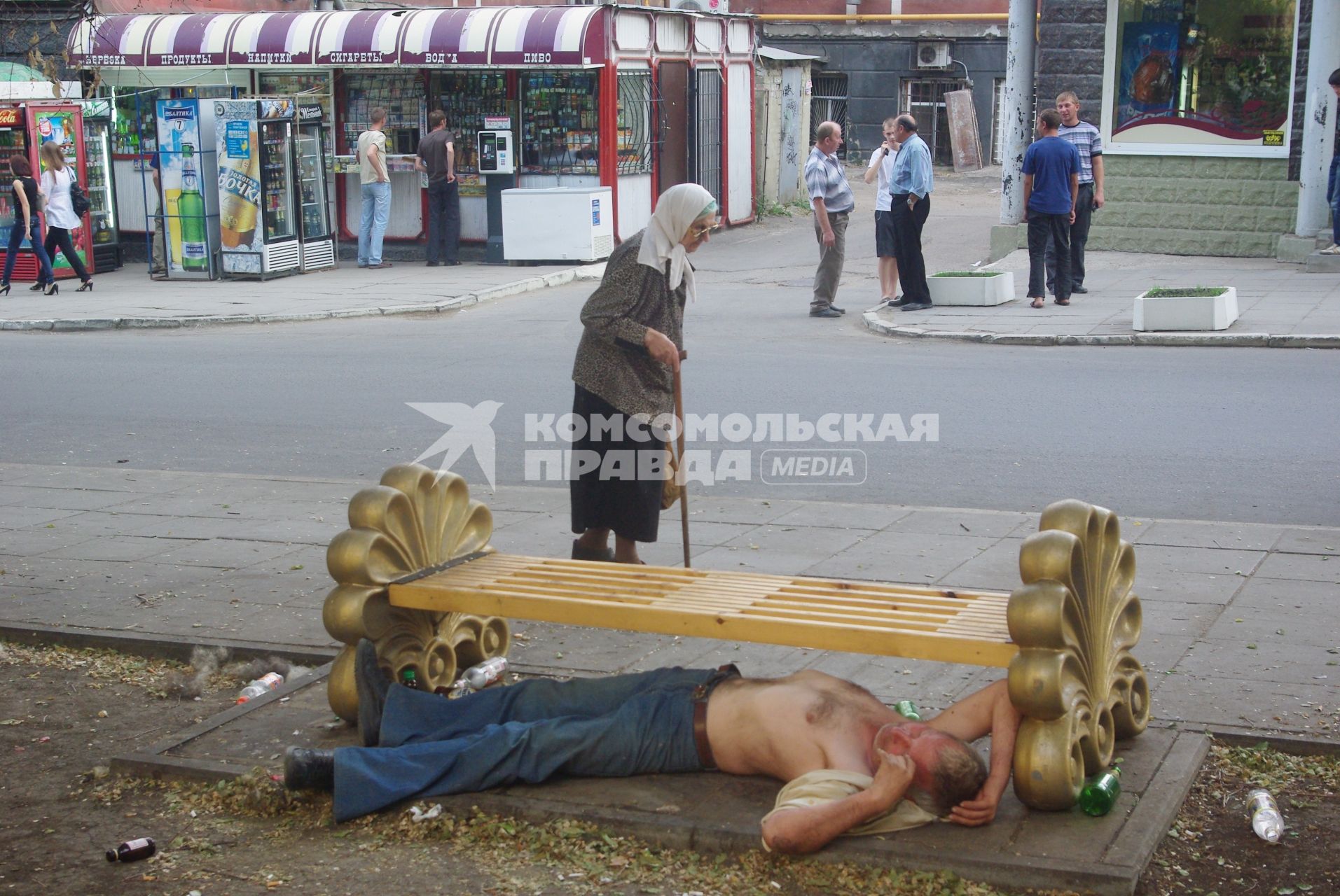 Бабка горестно проходит мимо спящего под лавкой молодого мужчины, 7 июня 2010 года. Старики. Пенсия. Пенсионная реформа. Молодежь. Алкоголизм. Алкоголь. Россия. Пьянство. Пьяница. Пиво. Водка. Смерть пришла. Смерть с косой.