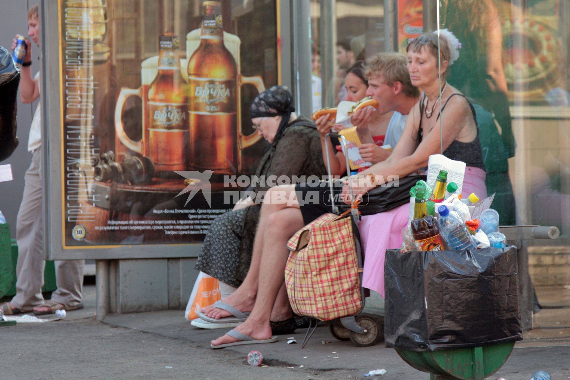 Люди на остановке общественного транспорта, Москва, 18 июля 2010 года. Еда. Фаст фуд. Мусор. Экология. Мусорное ведро. Уборка улиц.