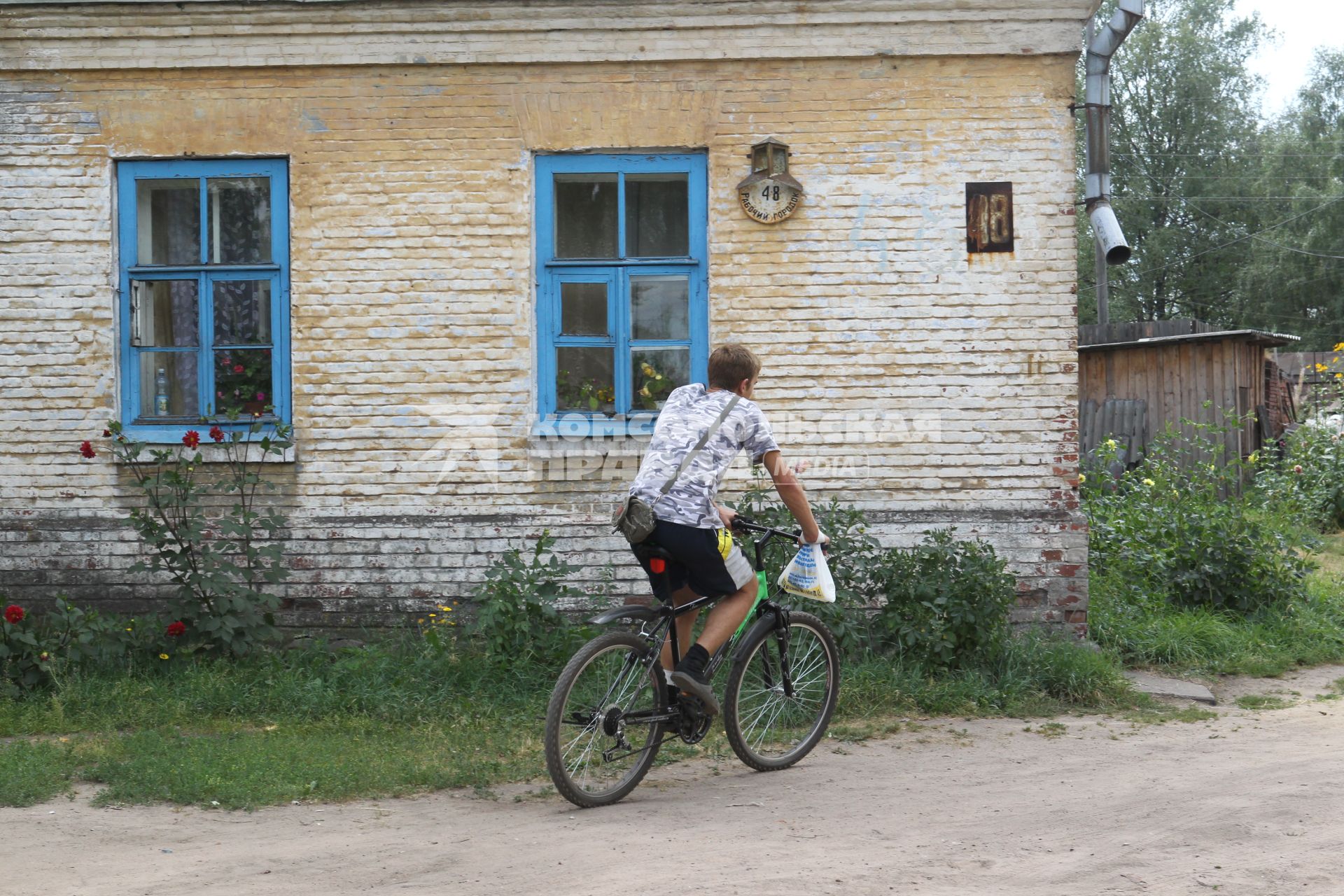 г. Осташков Россия Тверской области. 31 июля 2010 год. частный жилой дом, местный житель на велосипеде,  велосипедист, велосипед