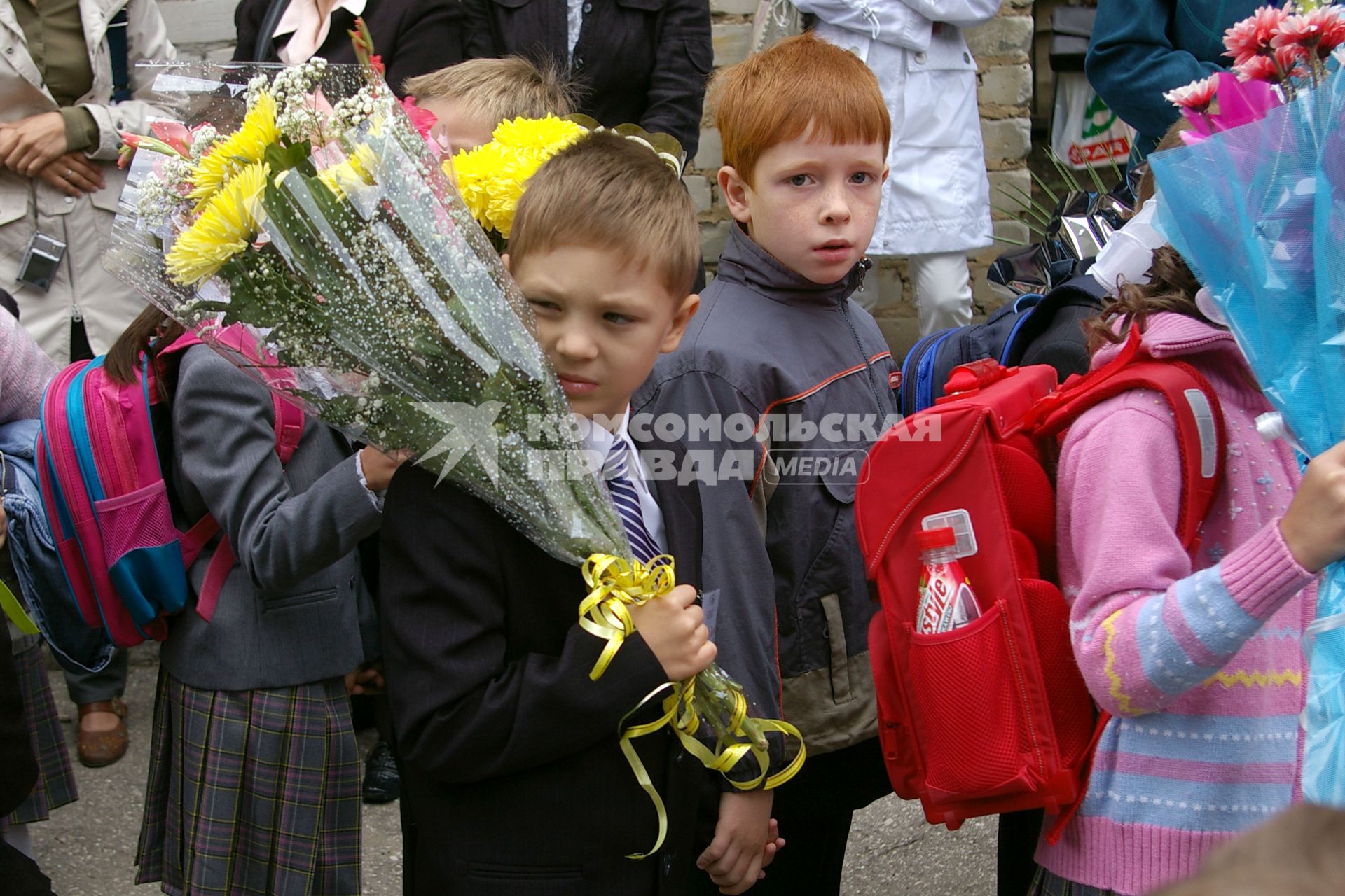 Первоклассник на школьной линейке с цветами груснтно смотрит на уходящее беззаботное детство, 1 сентября 2009 года.Саратов. Школа. Школьники. 1 класс. Форма. Дети. Детство. Ученик. Ученица. Учеба. Цветы. Линейка школьная.