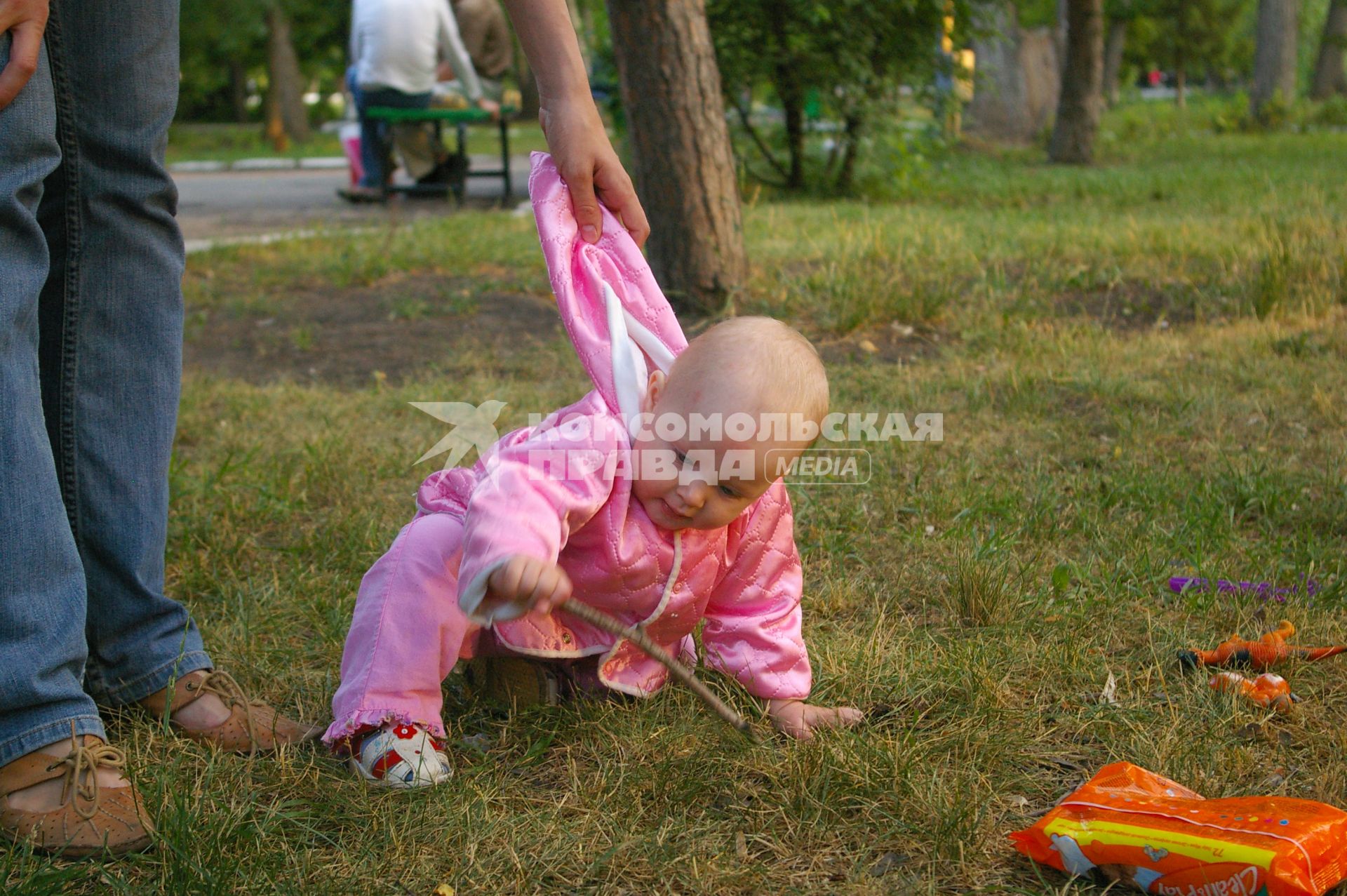 Падающего ребенка держит за капюшон мама,30 июня 2009 года. дети. Родители. Забота. Мама. Детство. Ушиб. Лето. Трава.