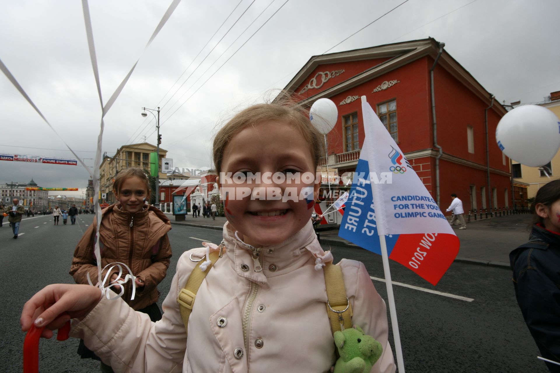 1 сентября 2007 года. День города. Девочка с триколором на щеке. Праздник.  Шарик. Флажок. Улица. Дом. Здание.