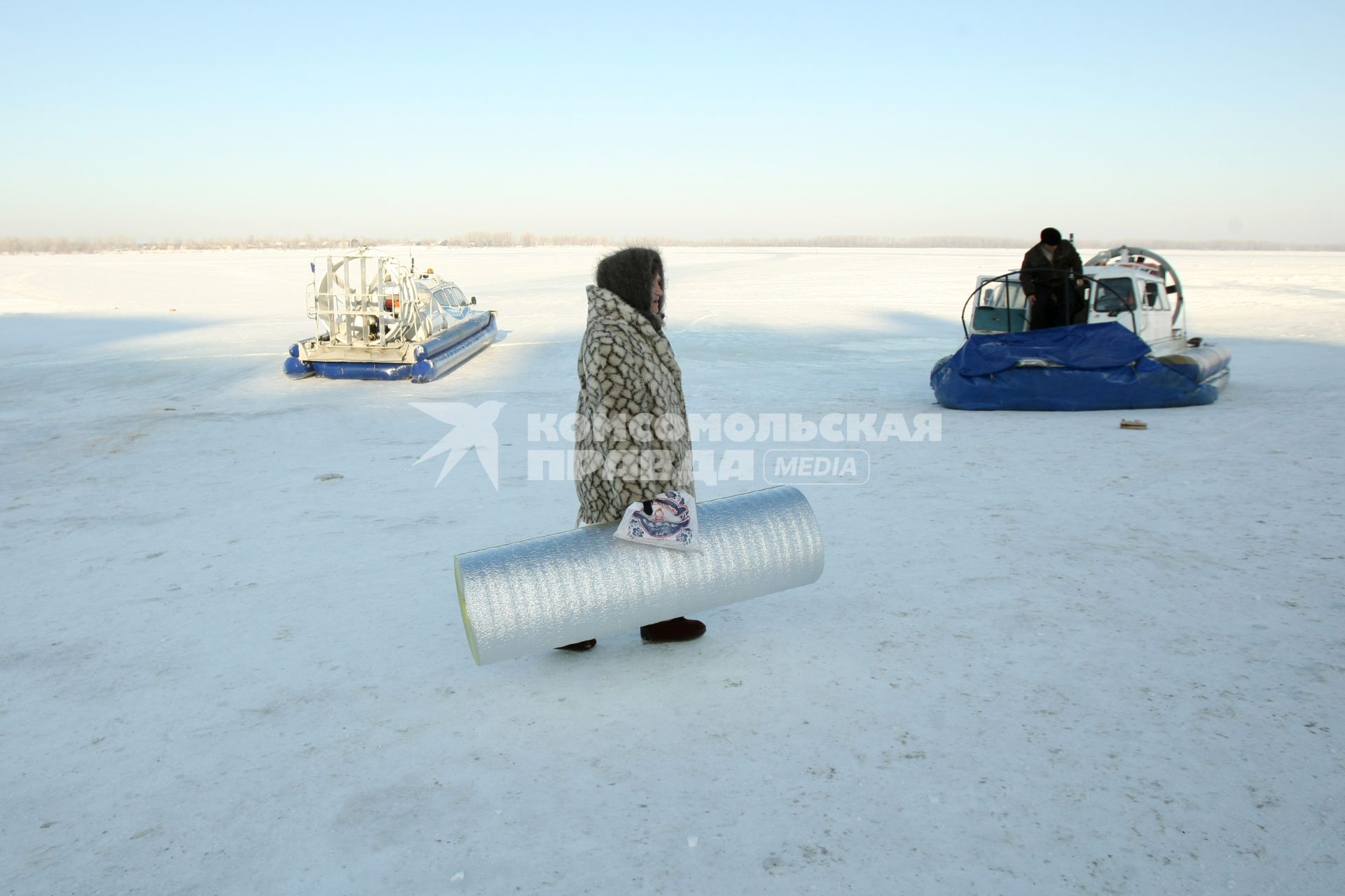 22.01.2010 Самара, Россия. Женщина зимой на берегу Волги идет на переправу на судно на воздушной подушке.