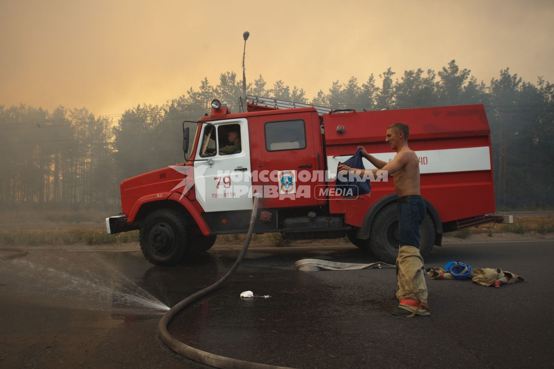 03.09.2010 Тольятти, Россия. Пожарный мочит водой одежду, чтобы спастись от перегрева на тушении лесного пожара.