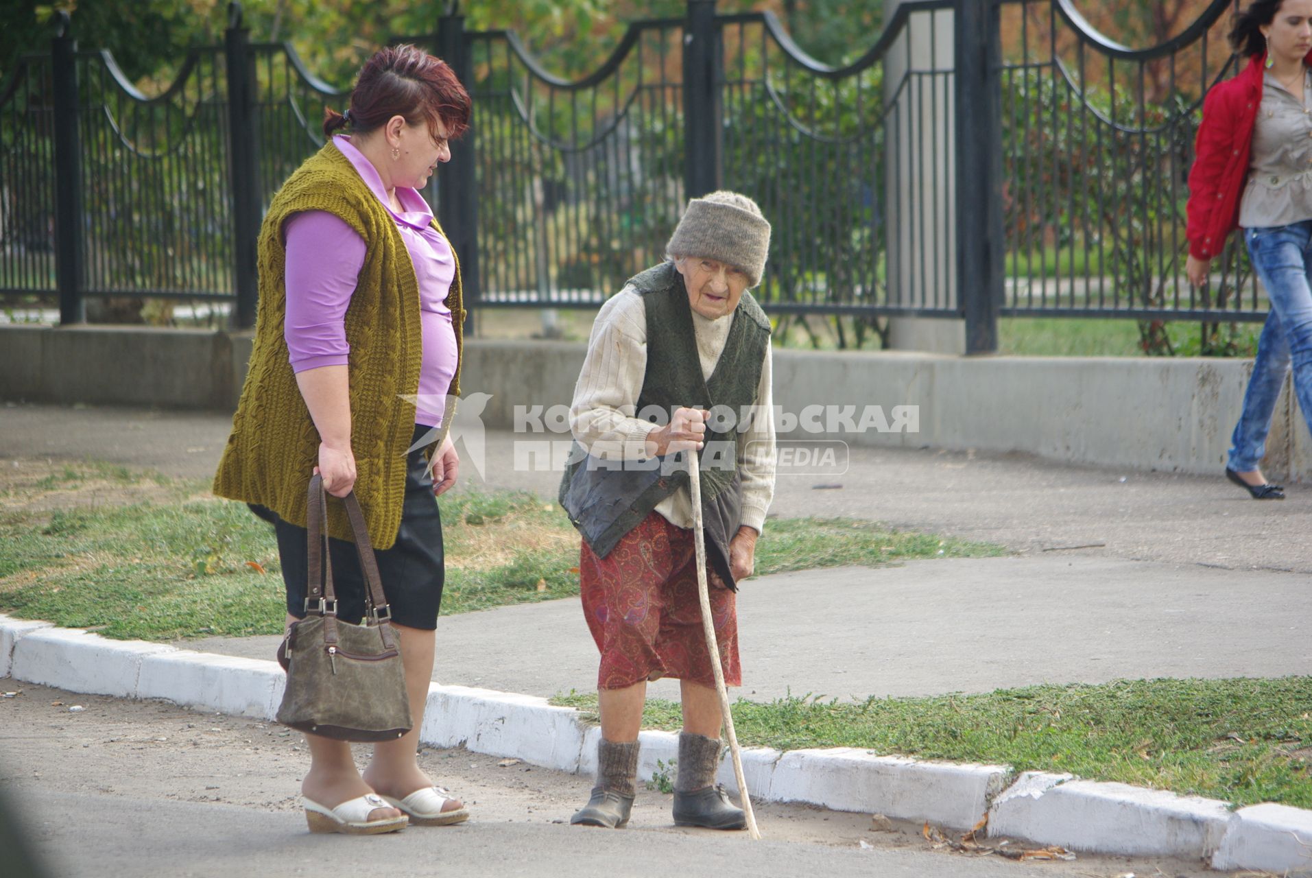 Бабулька с палочкой из ветки дерева, в галошахи фуфайке на улице города, 28 сентября, Саратов. Старость, пенсия, пенсионная реформа, радикулит, возраст, бабушка, бабка, пенсионер, социальынй работник, помощь.