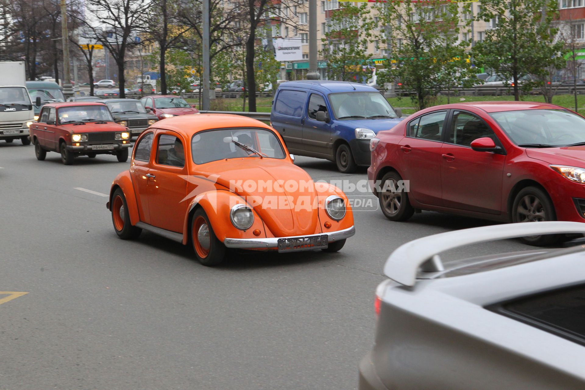 Оранжевый Volkswagen Beatle едет в потоке машин. 10 ноября 2010 года.