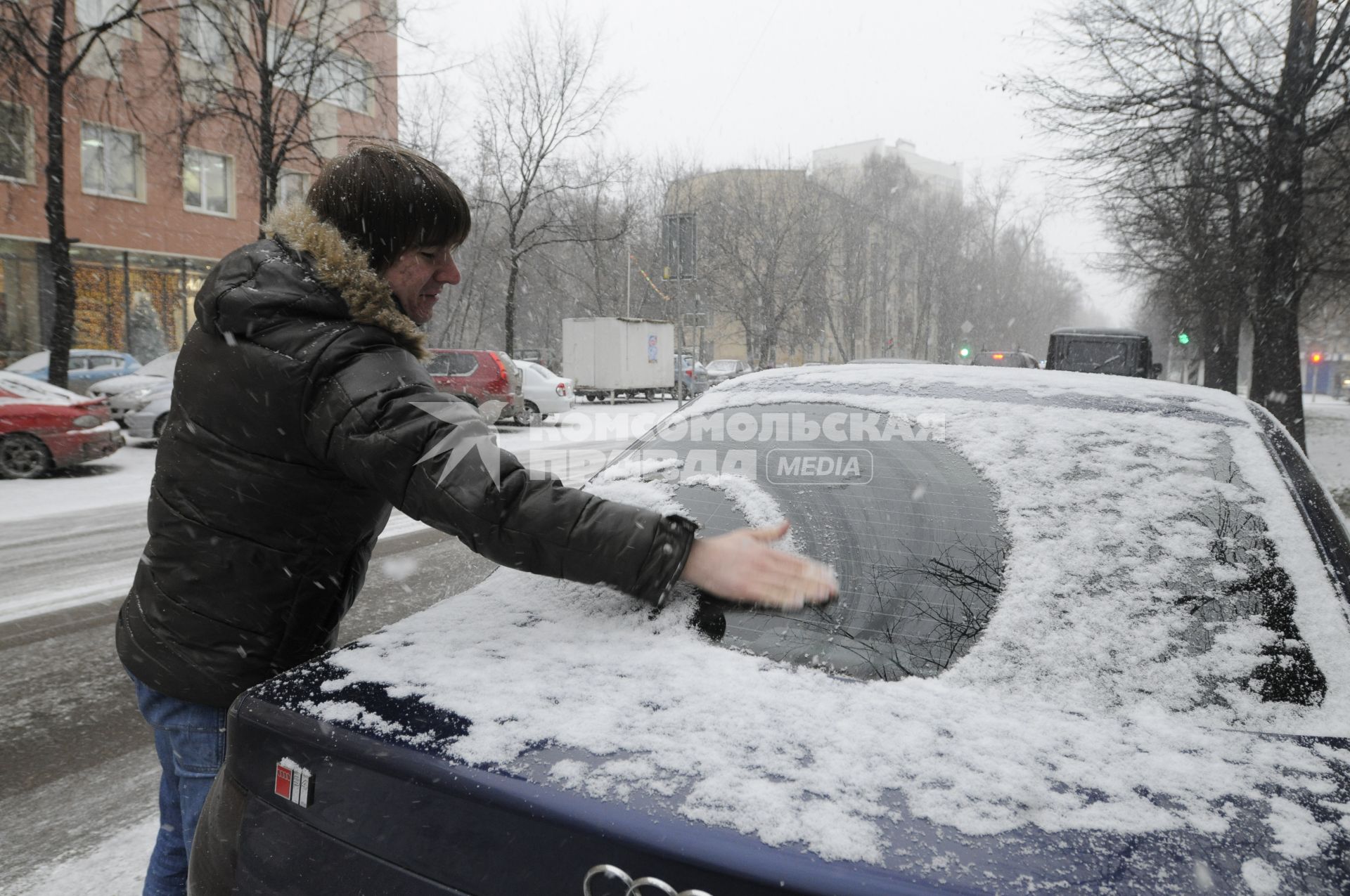 7 декабря 2009 года. Снегопад. Молодой человек сметает со стекла автомобиля снег.