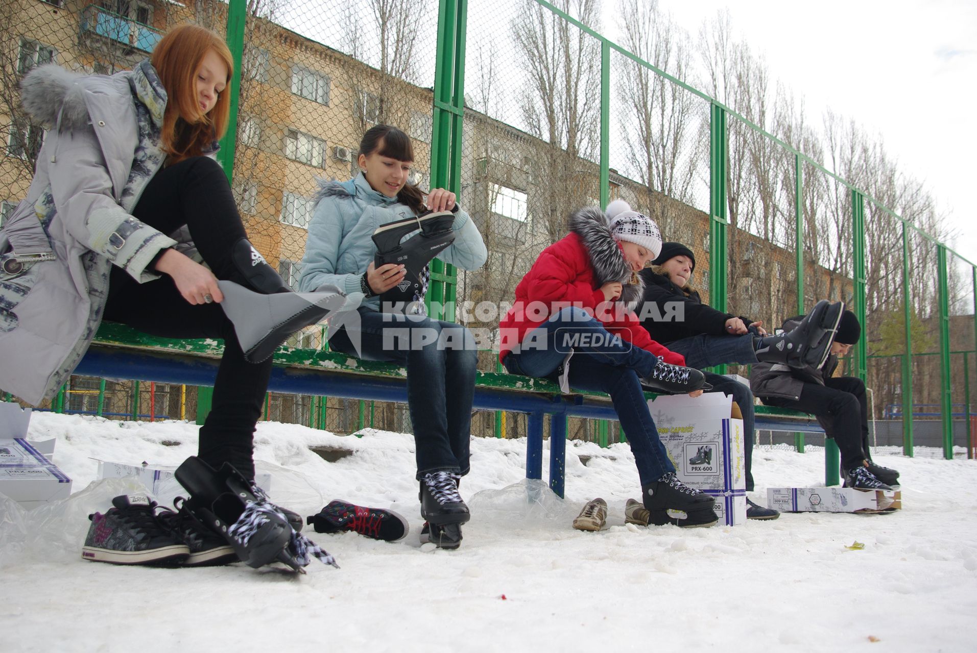 Дети одевают коньки сидя на лавочке перед школой, 22 декабря 2010 года, Саратов. школьники, дети, каток, коньки, зима, зимние забавы, каникулы, развлечения, отдых, мальчики и девочки, школа, перемена, урок физкультуры, закалка.