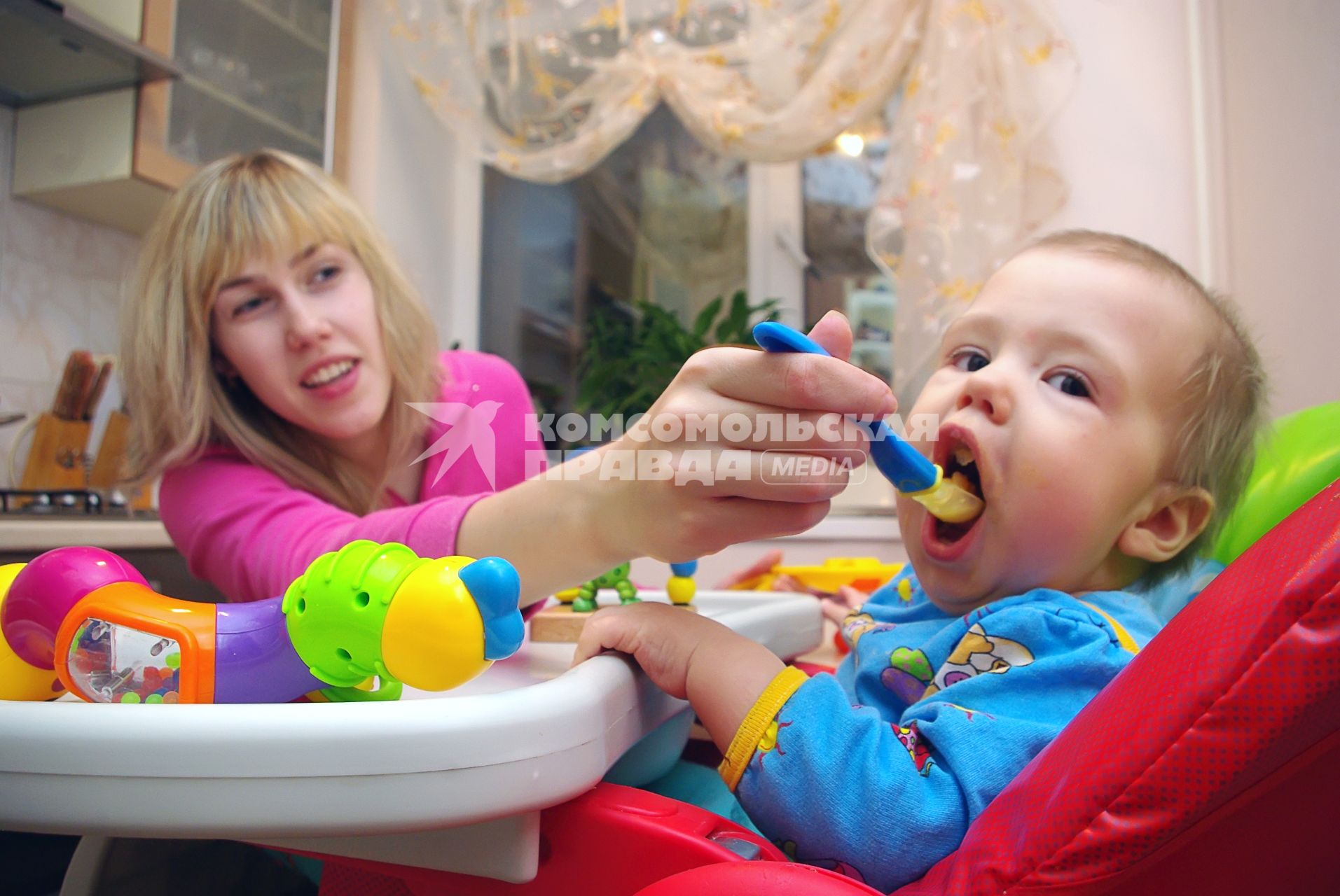 Молодая мама кормит ребенка из ложки, 15 января 2011 года, Саратов. Дети, еда, витамины, кормление, малыш, мальчик, дите, ложка, детское питание, родители и дети, детское кресло, аппетит, сын