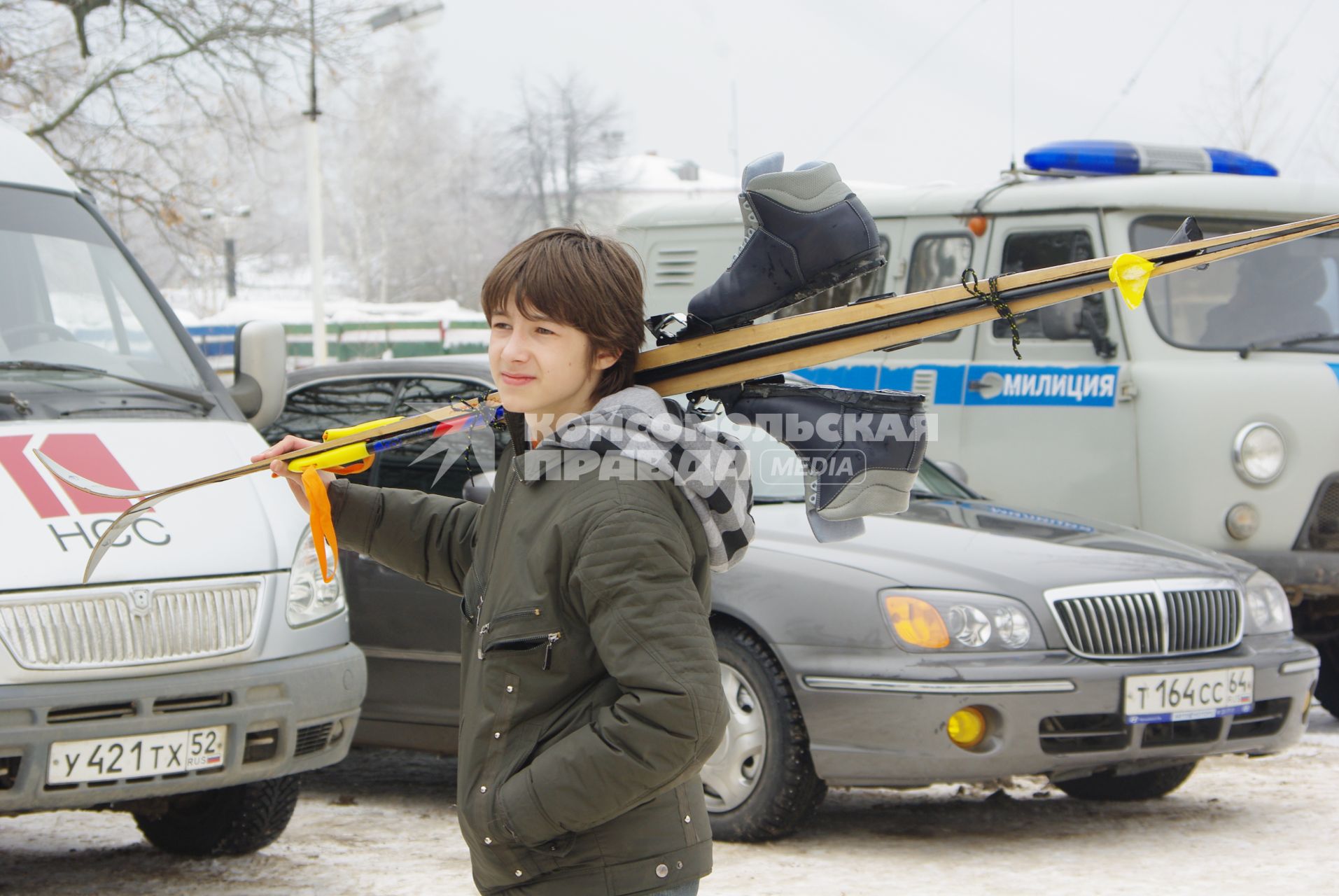 Мальчик несет на плече лыжи с ботинками, Саратов, 14 февраля 2010 года. Лыжи, лыжники, лыжный забег, соревнование, конкурс, зима, спорт, здоровье, лыжная форма, зимние развлечения, отдых, зимние виды спорта, лыжные ботинки.