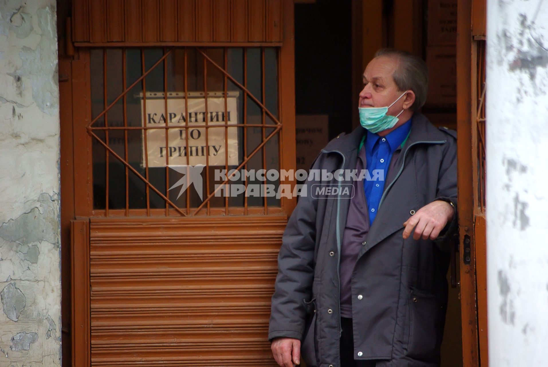 Мужчина в маске стоит у входа в здание, на котором висит табличка \"Карантин по гриппу\", Саратов, 4 декабря 2009 года. Карантин, грипп, свиной грипп, маска, эпидемия, болезнь.