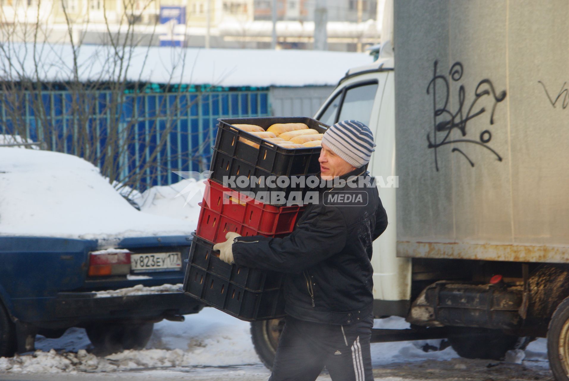 Грузчик несет контейнеры с хлебом. Доставка продовольствия. Хлеб. Продукты. Продовольствие. Зима. Мороз. 17 февраля 2011 года.