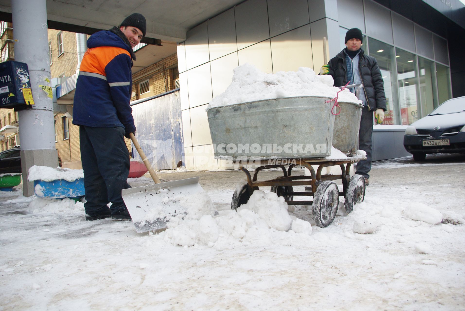 Гастарбайтеры убирают снег в корыто на тележке, Москва, 17 февраля 2011 года.