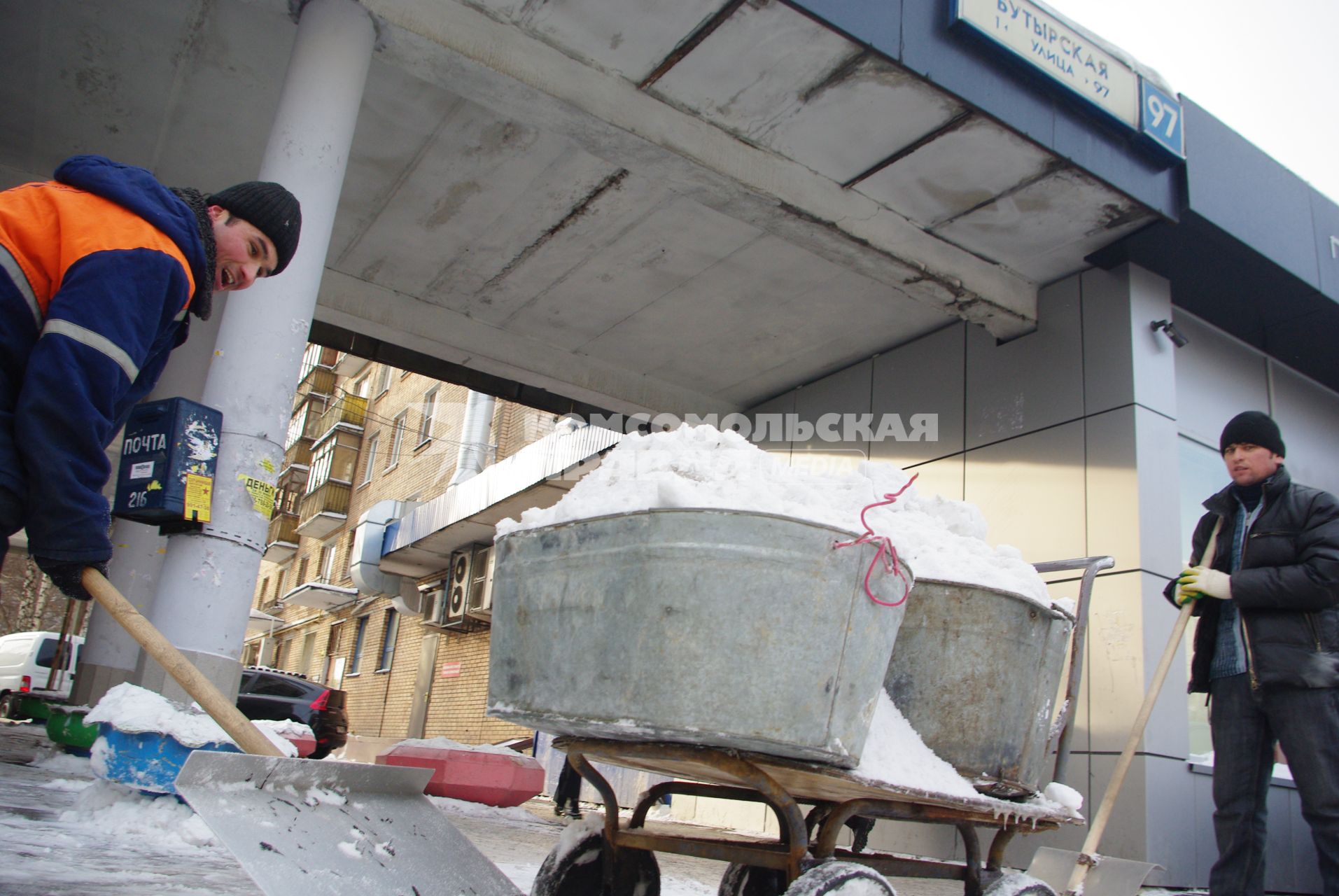 Гастарбайтеры убирают снег в корыто на тележке, Москва, 17 февраля 2011 года.